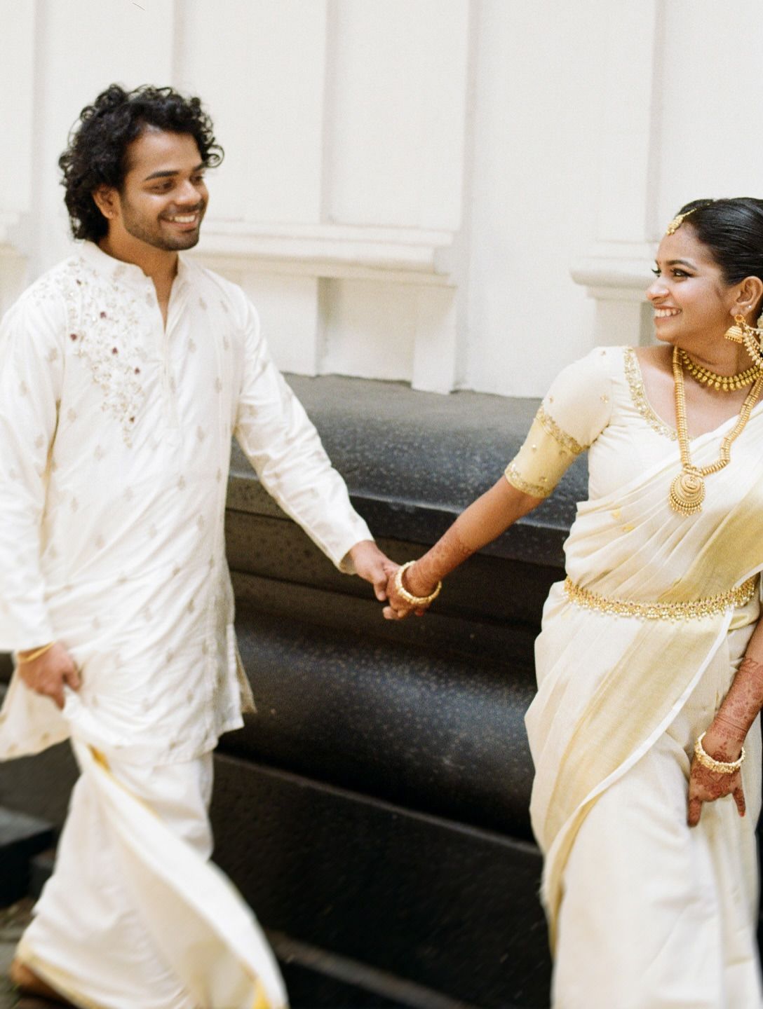 Vinay and Aswathy walking hand in hand in white, shot on 35mm film