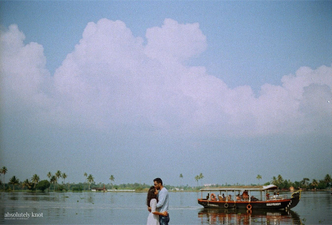A couple on the backwaters beside a boat under a wide sky, shot on 35mm Kodak film