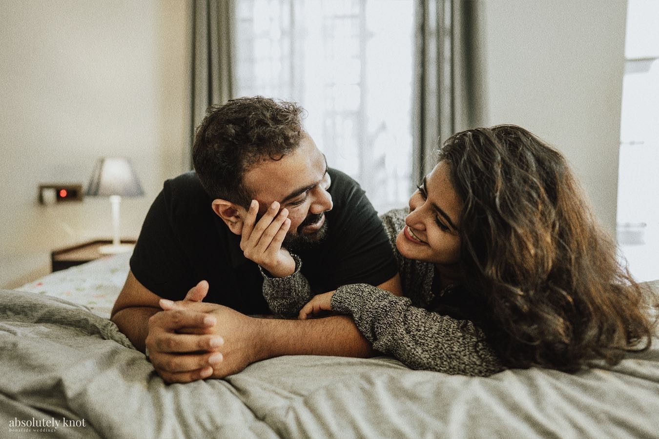 A couple lying on a bed, laughing together