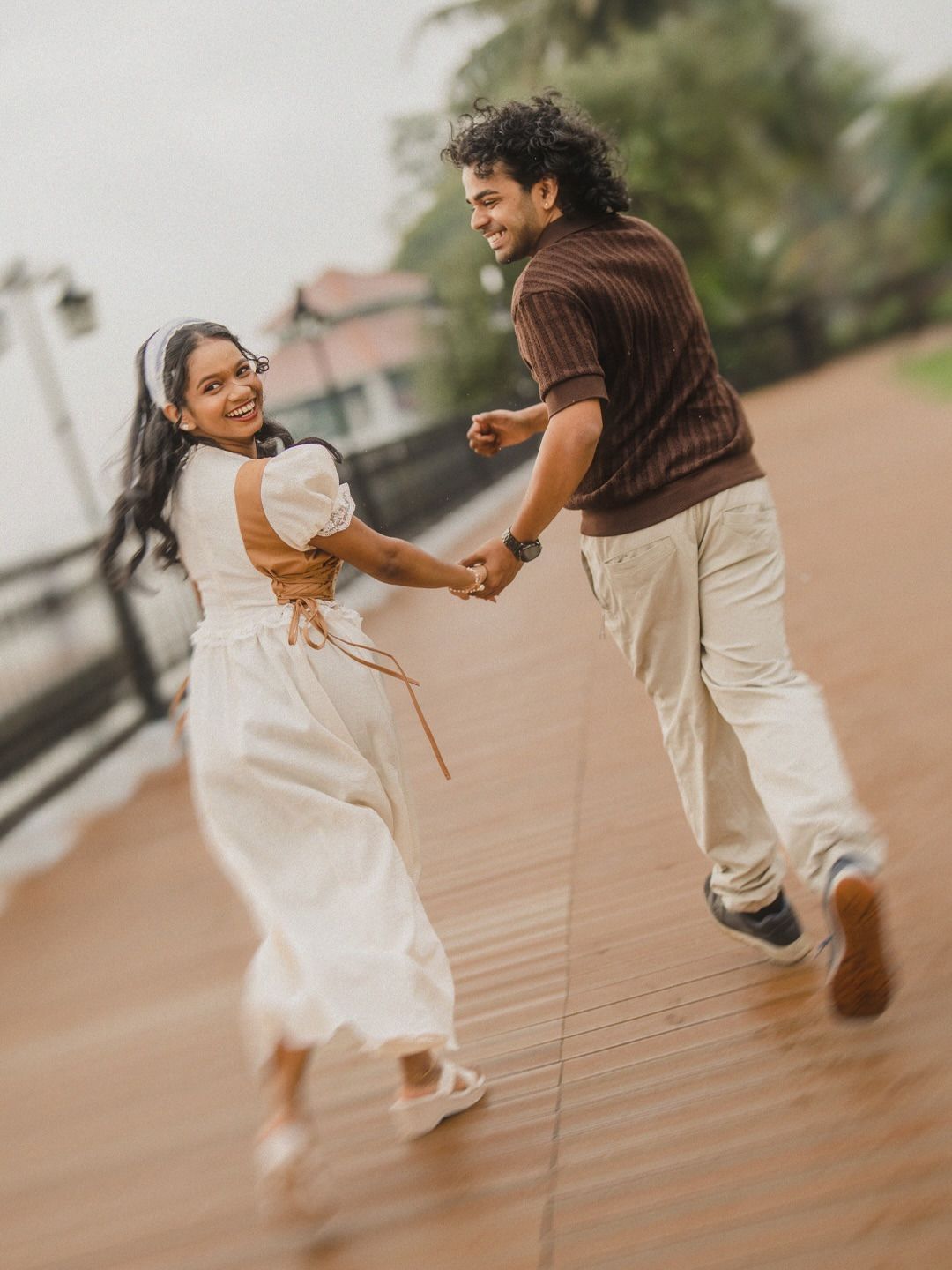 A couple running hand in hand along a wet wooden boardwalk
