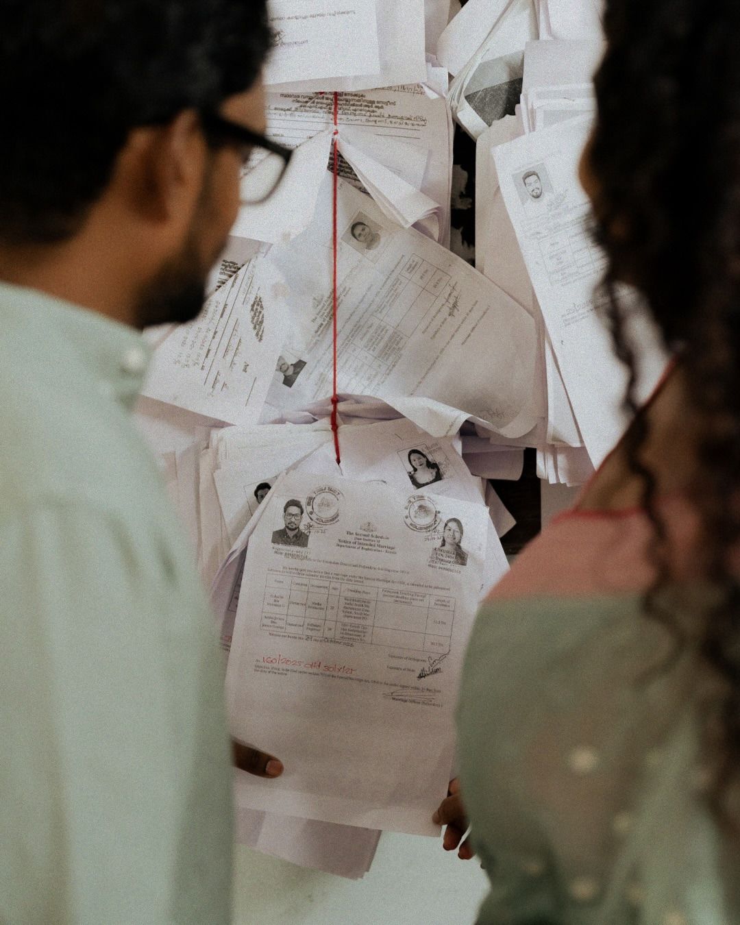 A couple at a registrar’s office, papers pinned to the wall between them