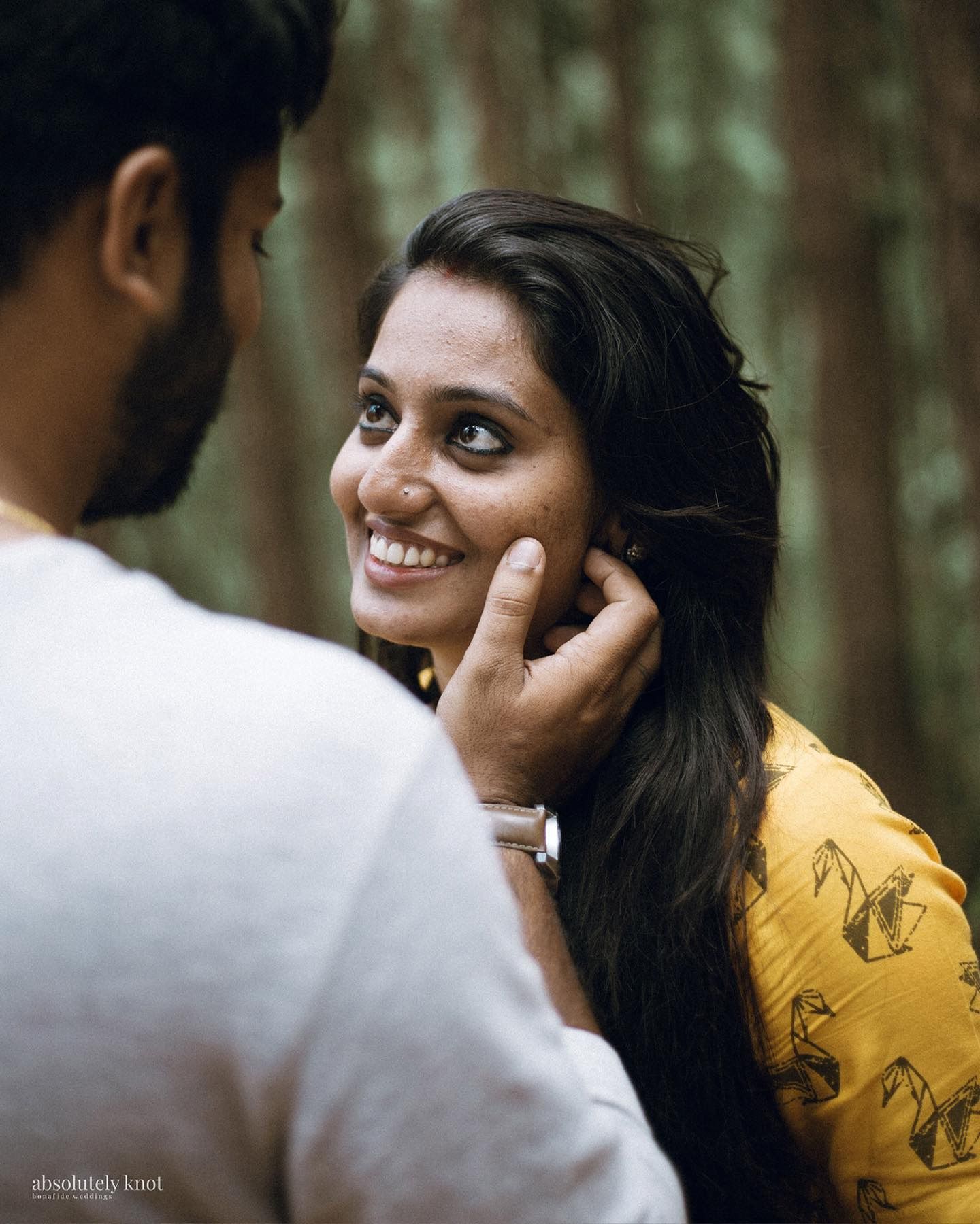 A woman smiling as she tucks her hair behind her ear