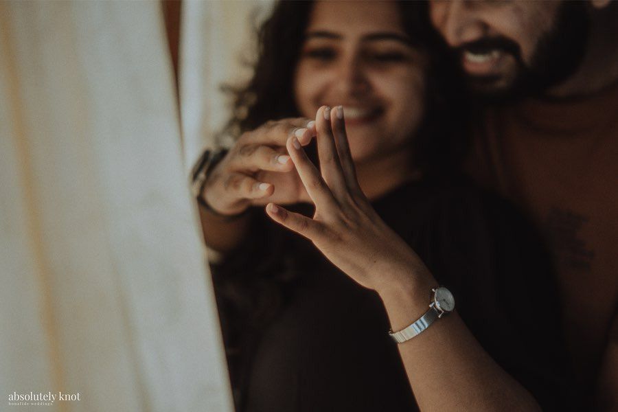 A couple making a heart with their hands and laughing behind it