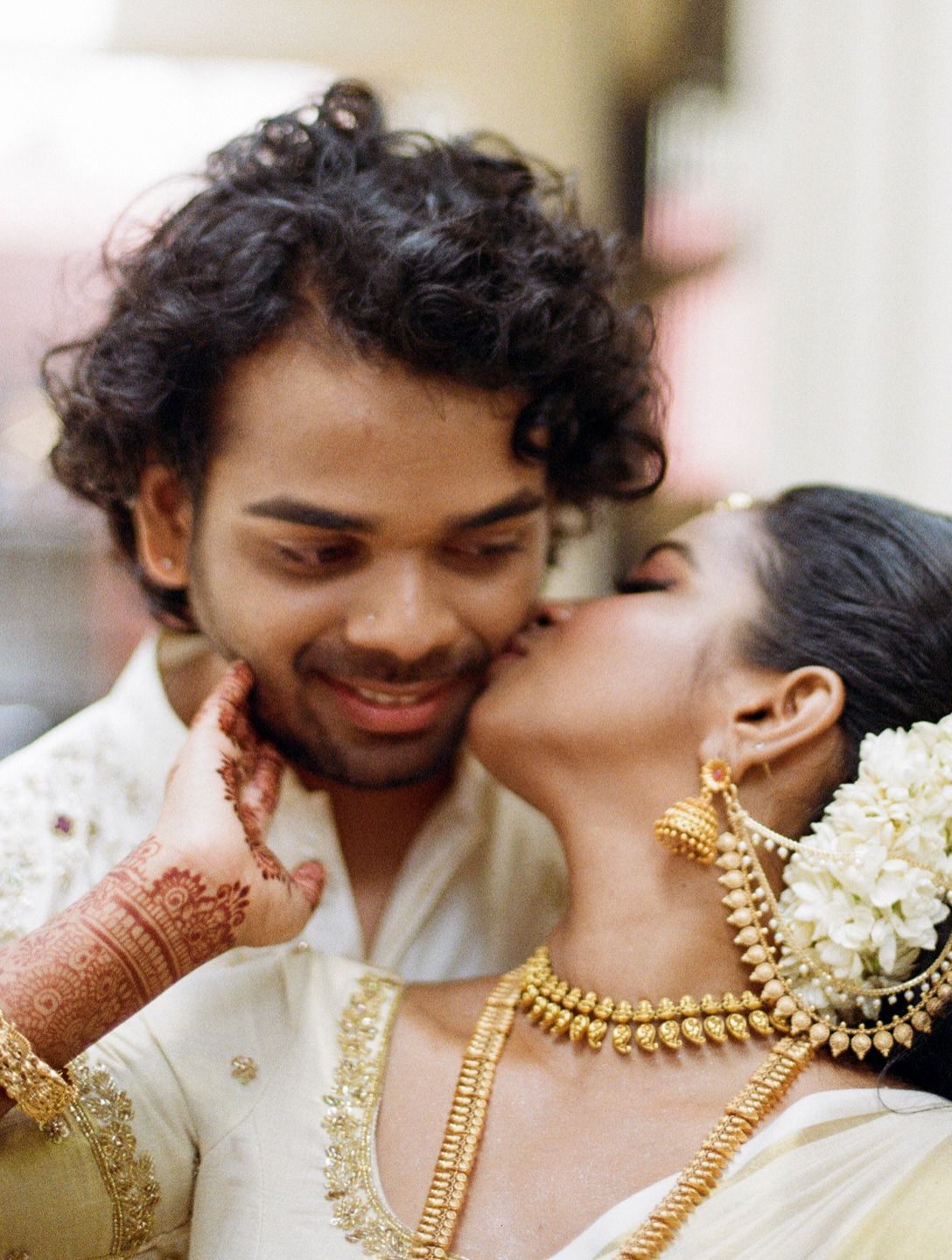 A bride kissing the groom on the cheek