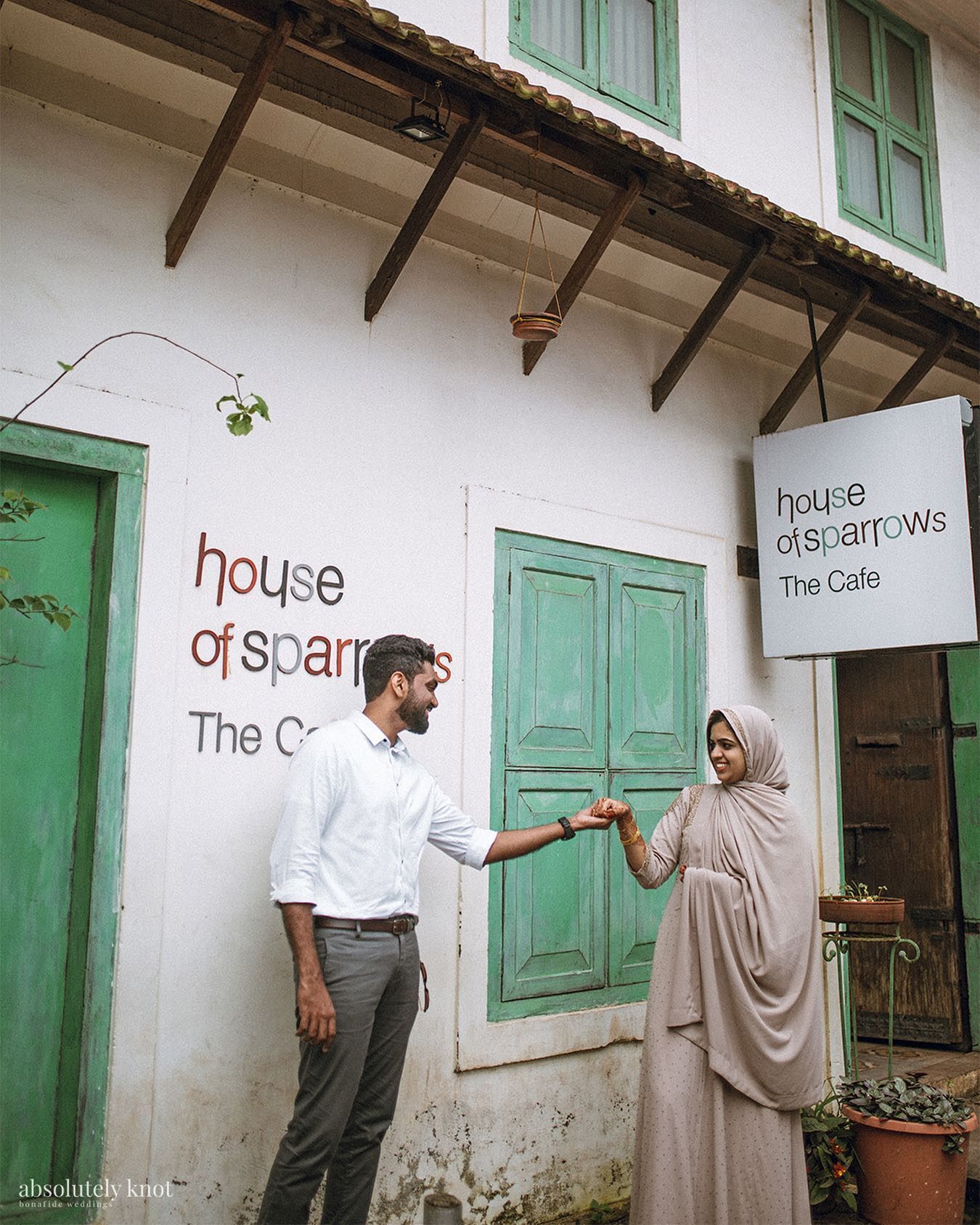 A couple holding hands outside a café with green doors